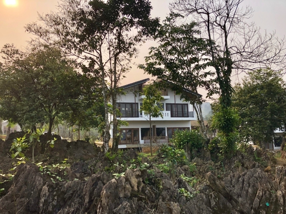 Maison entourée d'arbres et de paysage rocheux.