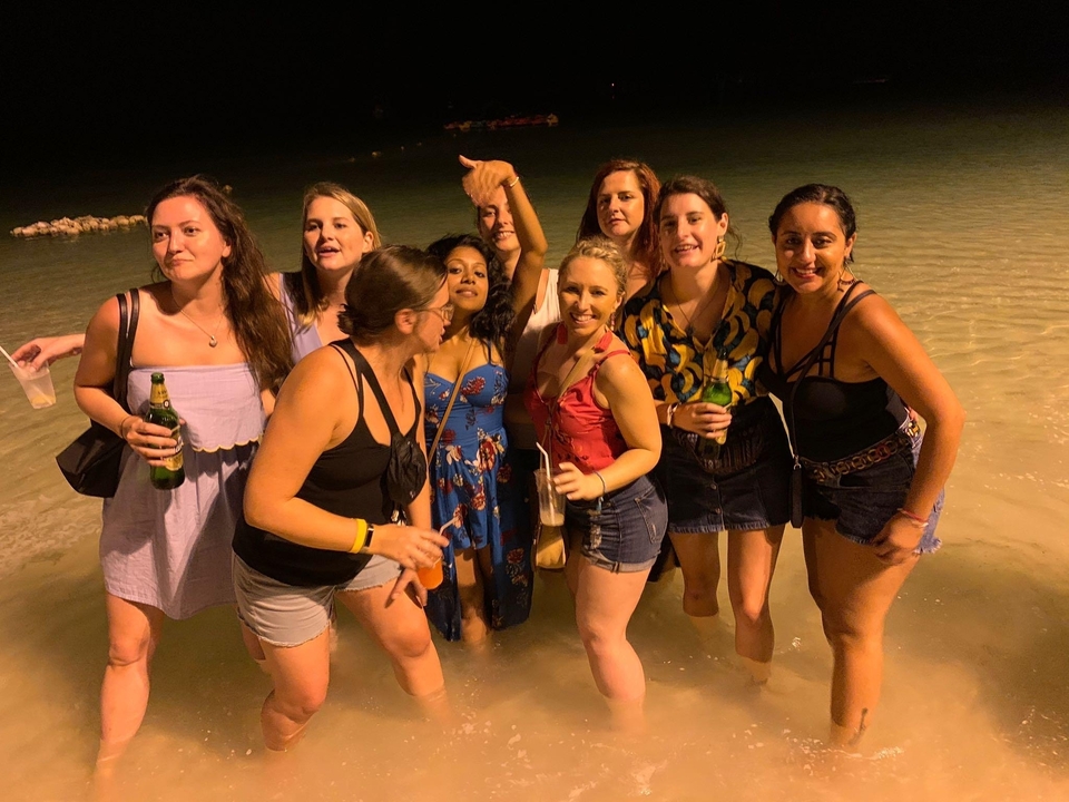 Groupe de personnes qui fait la fête sur la plage la nuit avec des boissons.