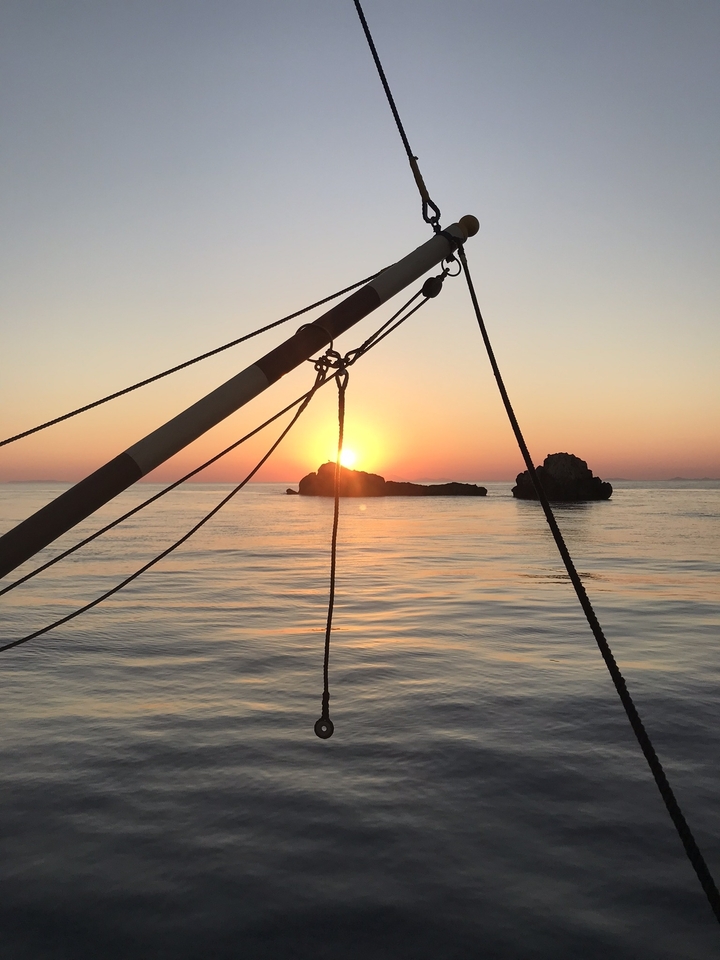 Silhouette of ropes and rocks with a sunset over the sea.