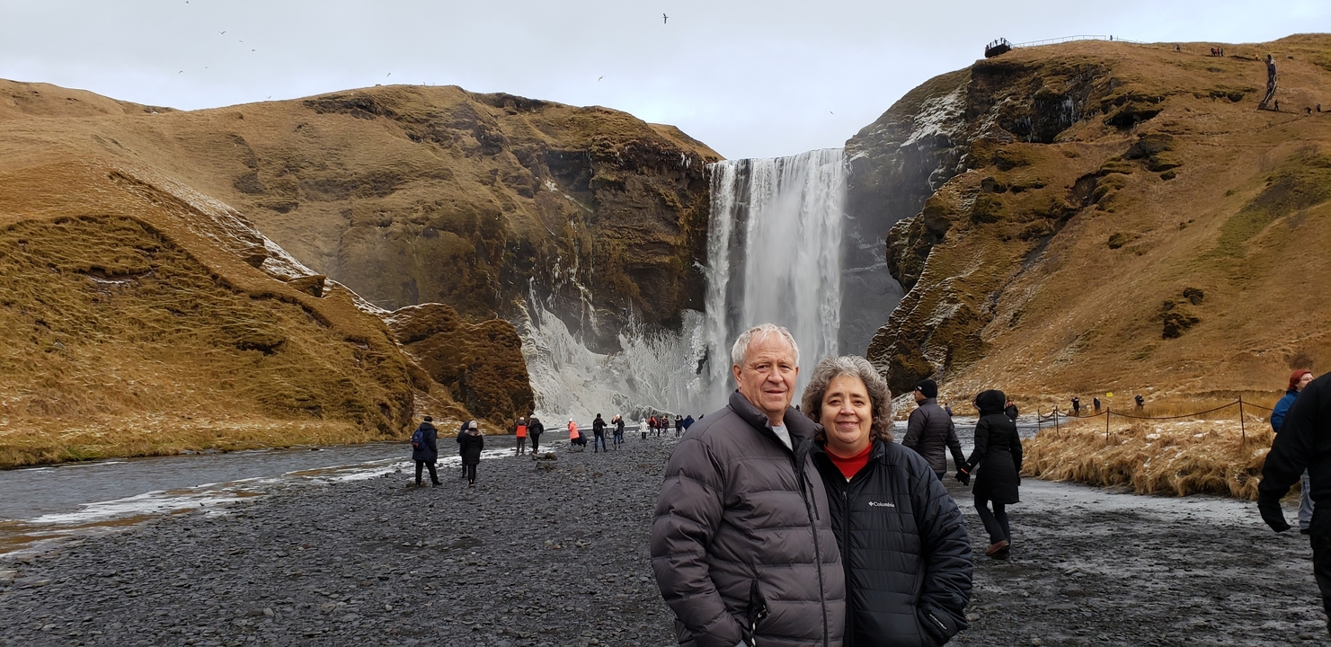 Couple standing in front of an impressive waterfall.