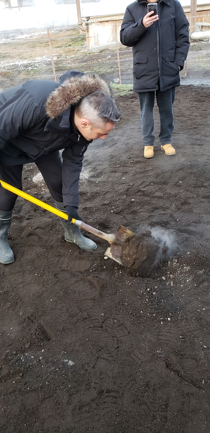 Person digging in the ground with yellow steam rising.