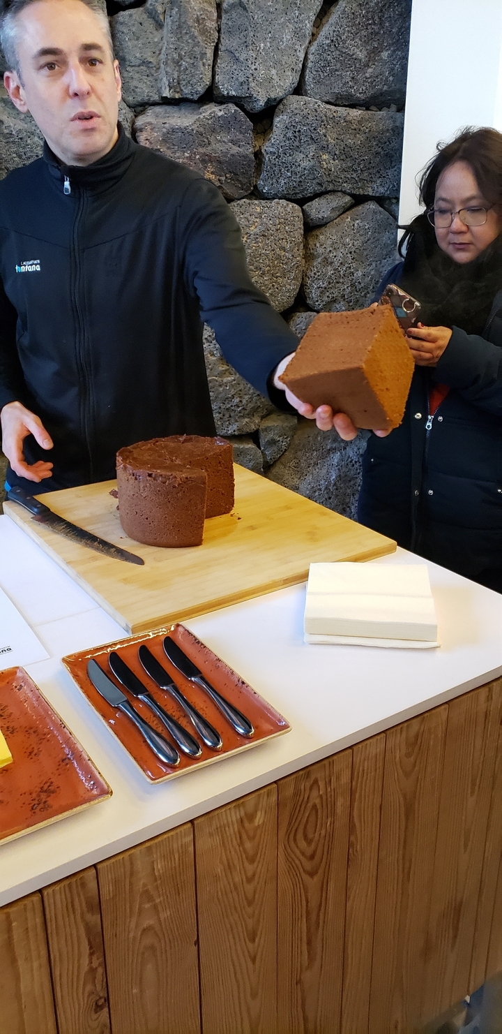 Person slicing baked goods on a wooden board.