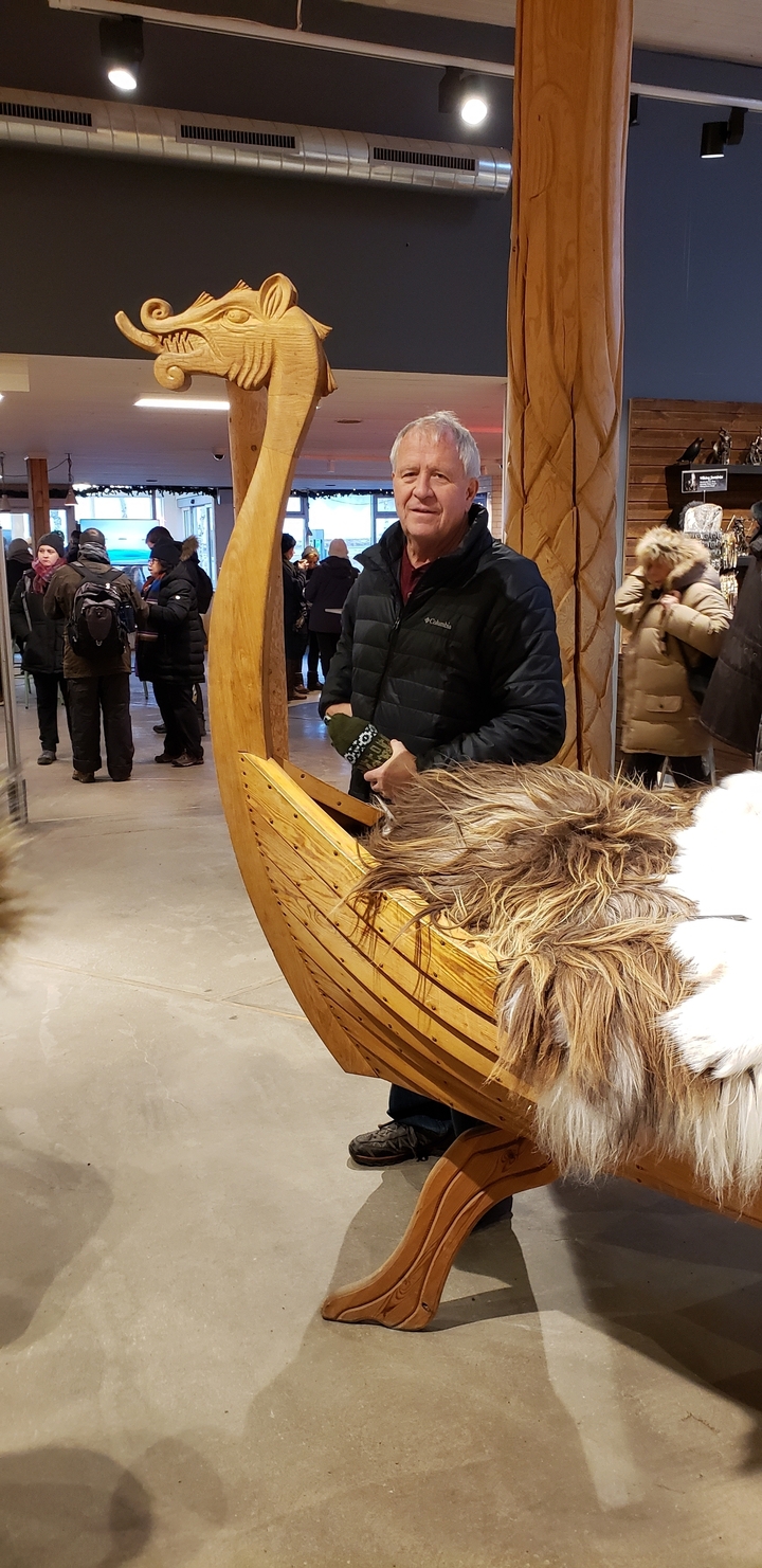 Person with a wooden boat-like structure indoors.