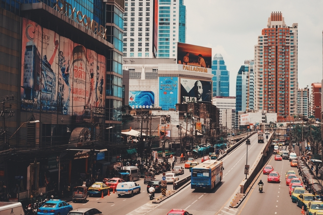 Paysage urbain animé avec panneaux publicitaires et circulation.