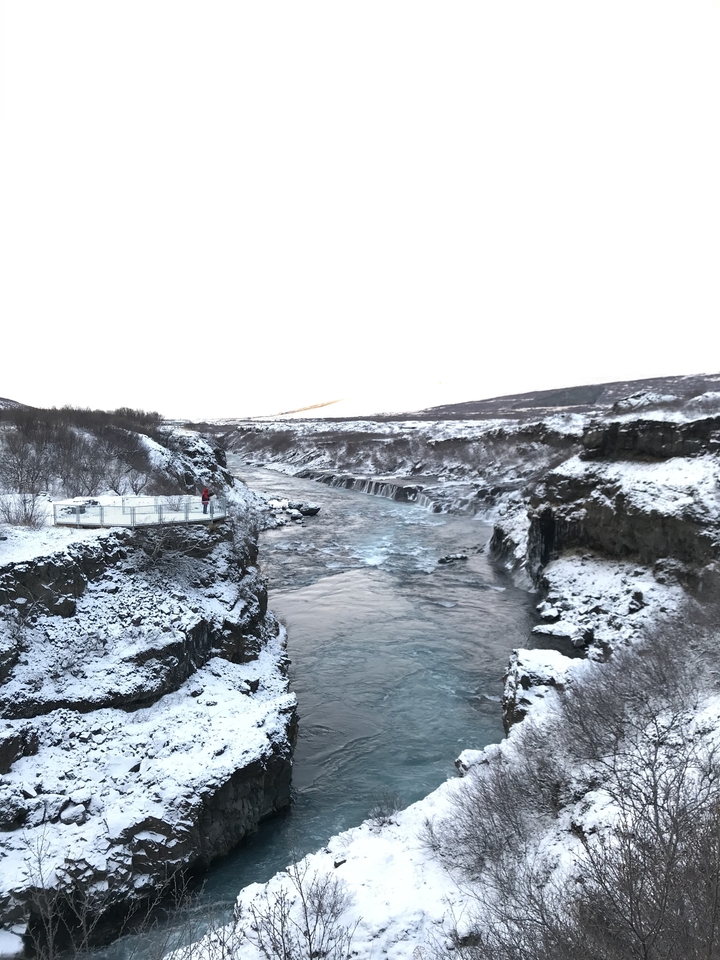 Snowy canyon with river and distant mountains.
