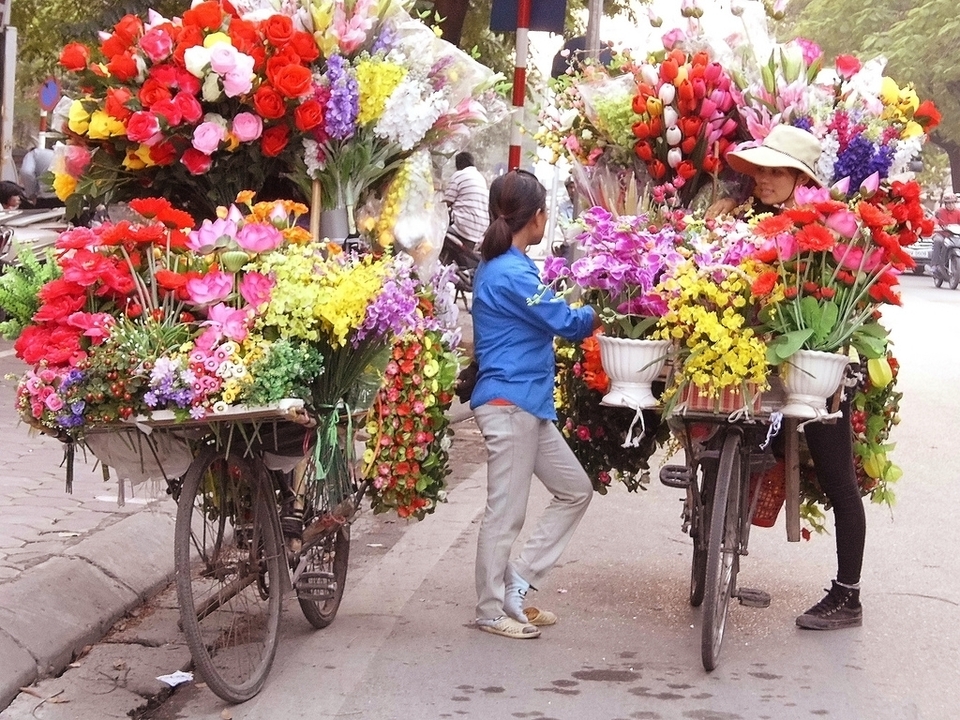 Deux femmes avec des vélos remplis de fleurs colorées.