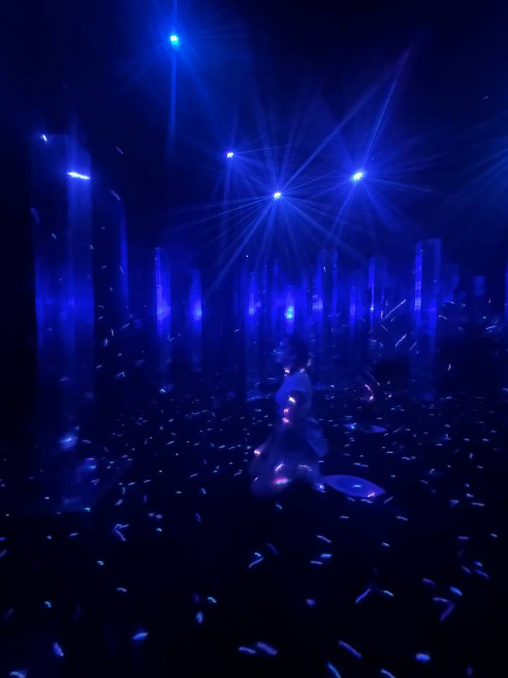 Chambre sombre avec des lumières bleues et une personne au loin.