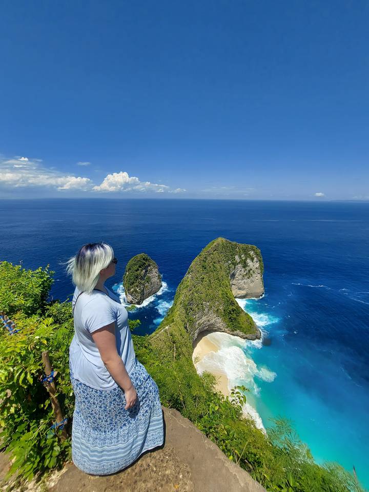 Une femme aux cheveux courts regardant au-delà d'une côte rocheuse.