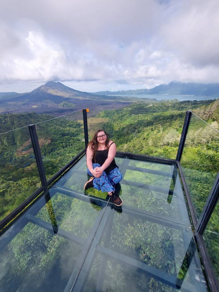 Une personne assise sur une plateforme en verre avec une vue panoramique.
