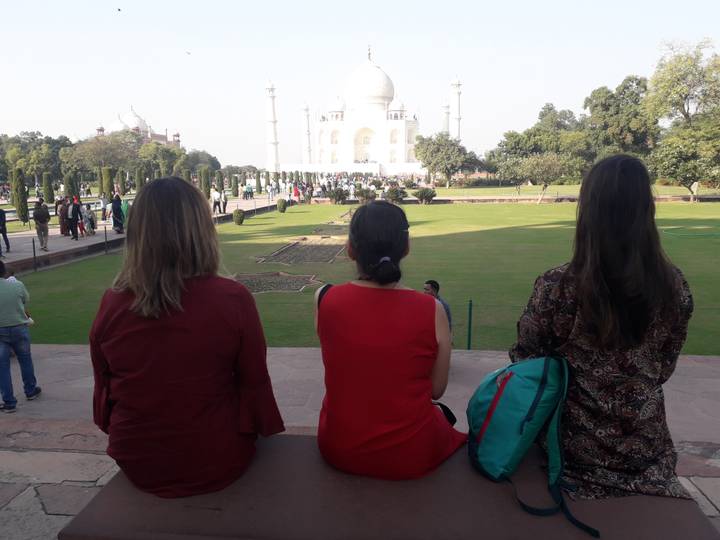 Three women sitting and looking at the Taj Mahal.