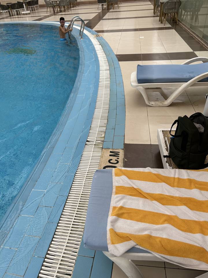 Poolblick mit einem Sonnenbadetuch auf einer Liege.