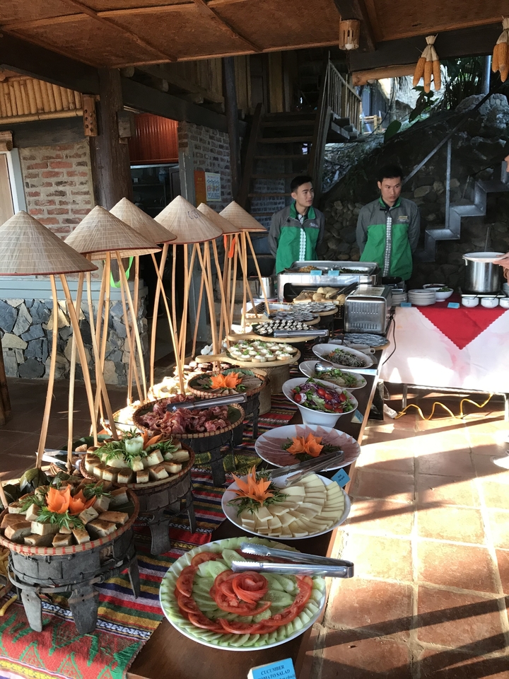 Buffet avec divers plats exposés, personnel en arrière-plan.