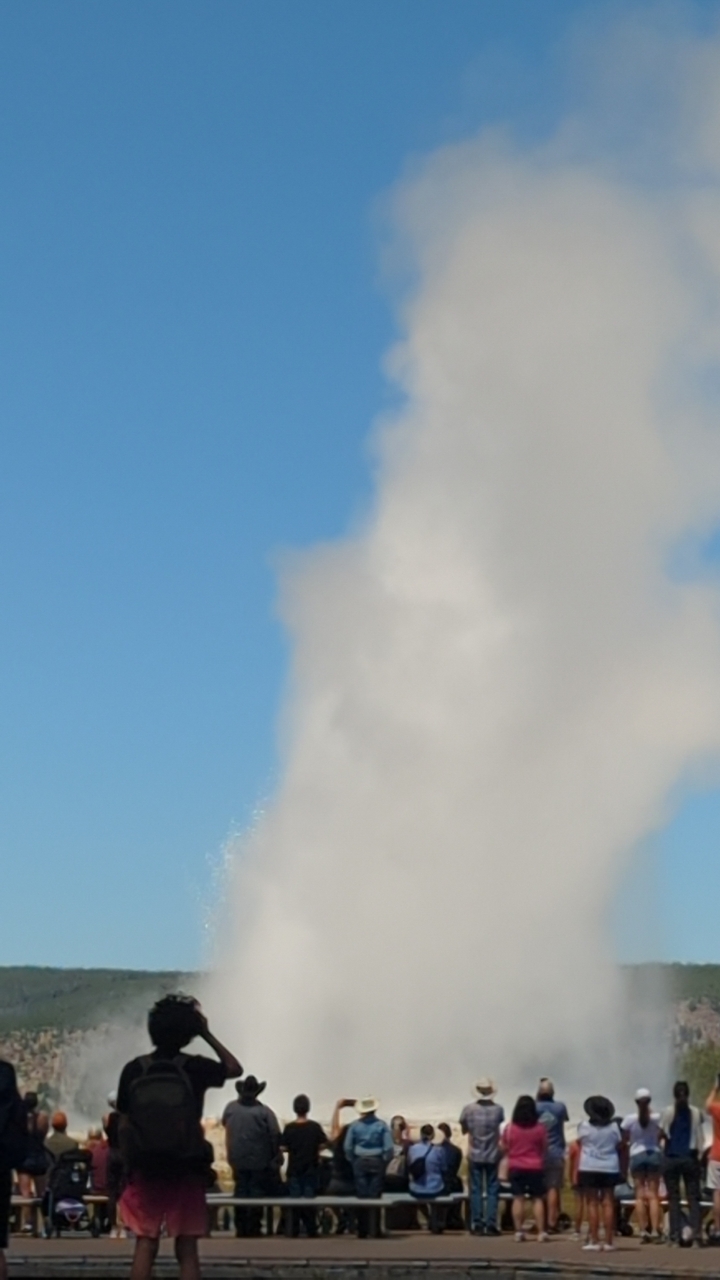 Un geyser en éruption contre un ciel bleu clair.