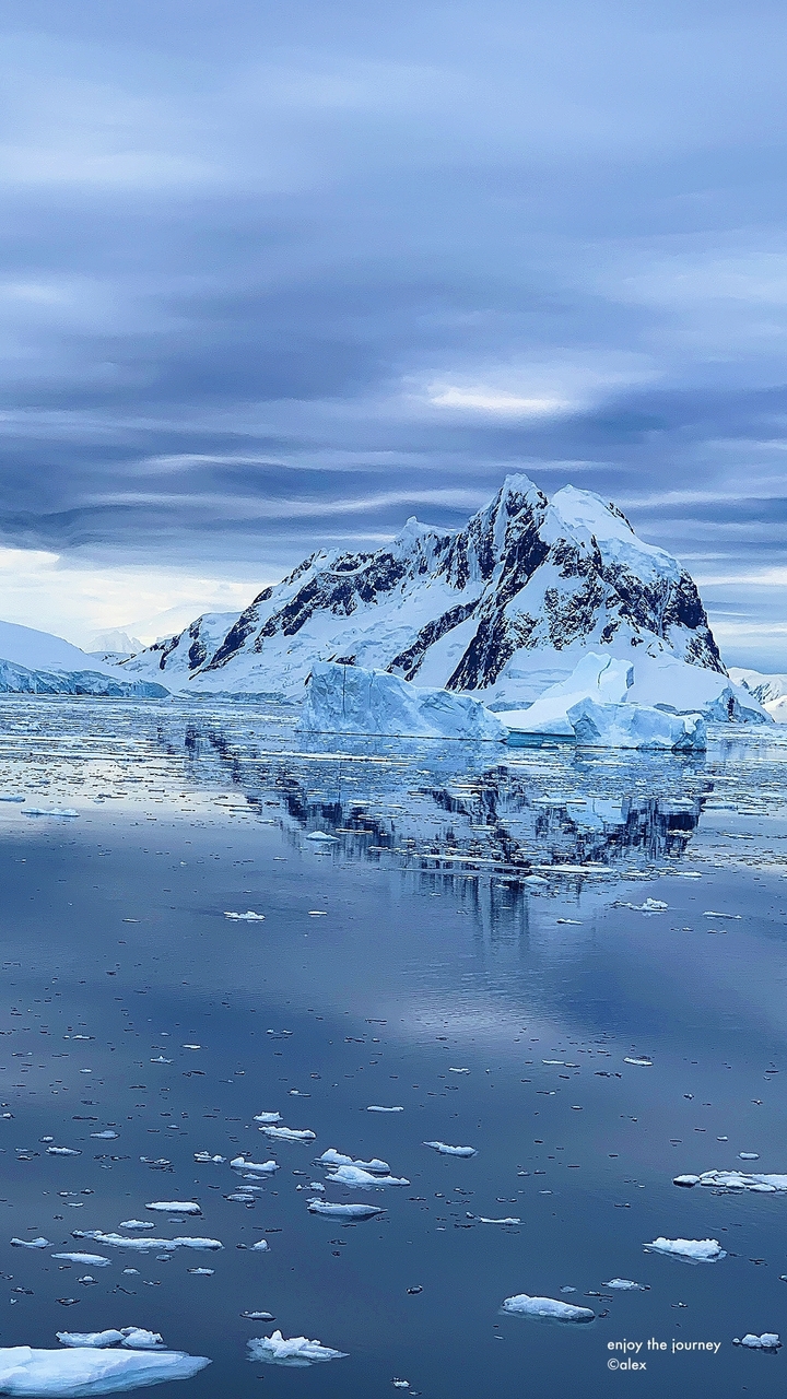 Iceberg flottant dans l'eau avec des montagnes couvertes de neige.