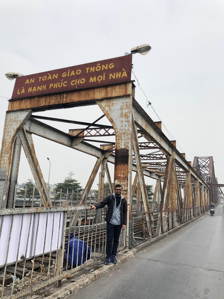 Personne debout sur un pont métallique rouillé.