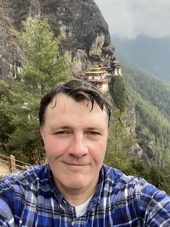 Personne avec un monastère à flanc de colline en arrière-plan.