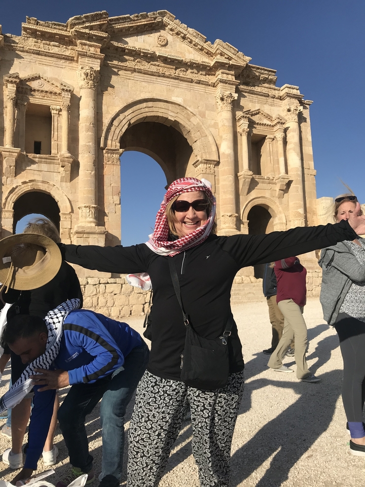 Personne souriante devant des ruines antiques.