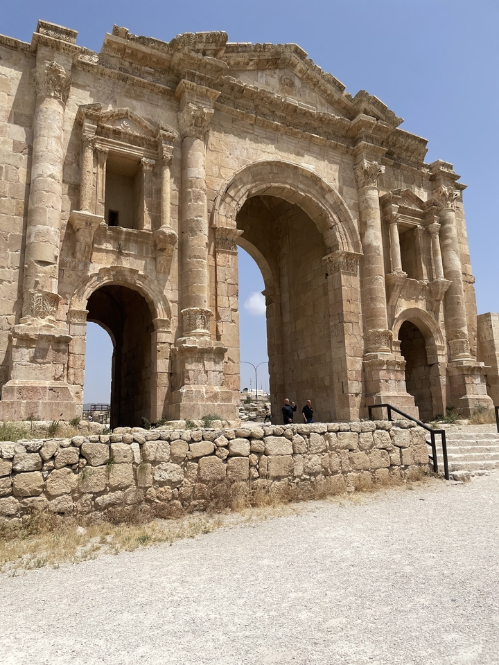 Arches de pierre historiques avec un ciel bleu et des gens à proximité.