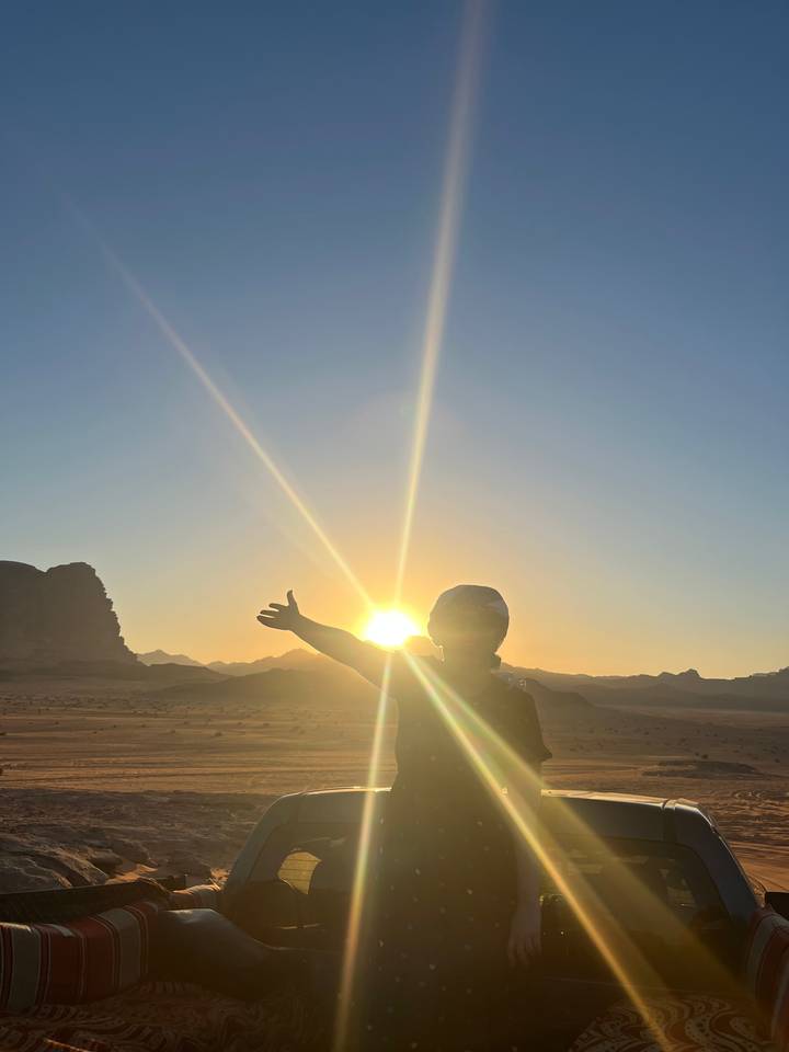 Silhouette d'une personne qui tend la main vers le coucher de soleil