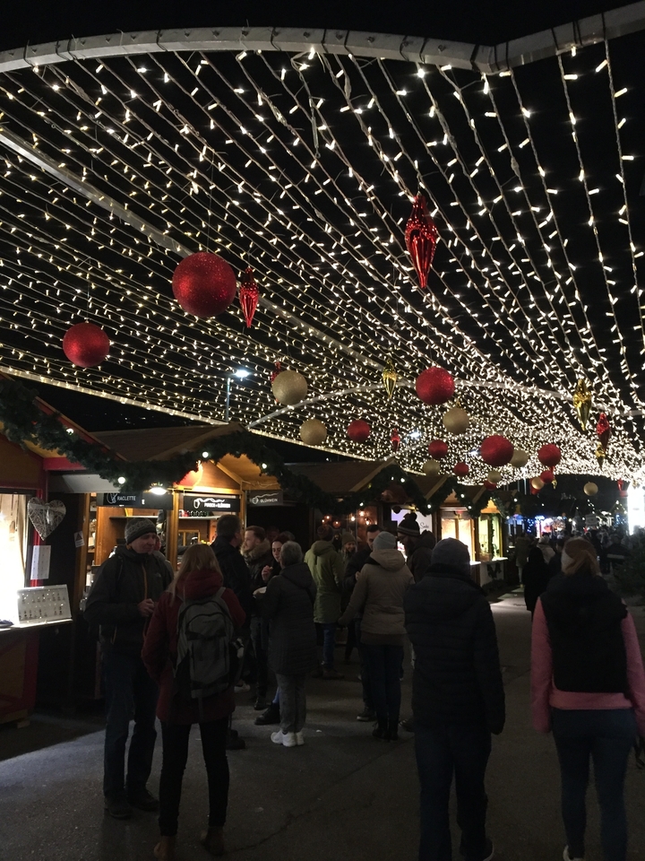 Des gens profitant d'un marché de Noël avec des lumières et des décorations festives.