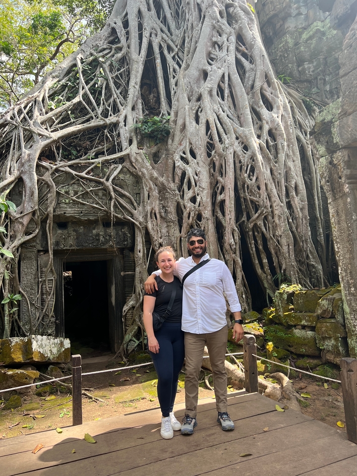 Touristes posant devant le temple de Ta Prohm avec des racines envahissantes.