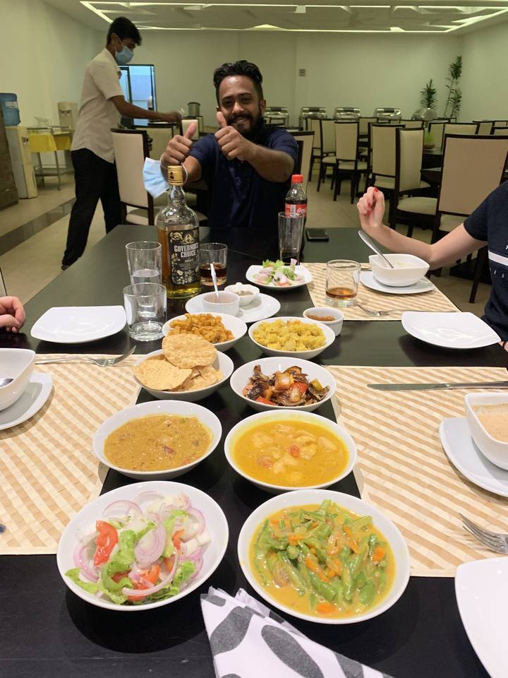 Table avec divers plats sri-lankais et des personnes en train de dîner.