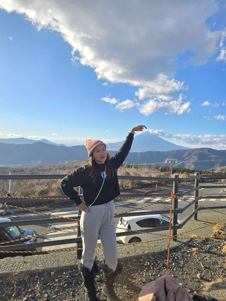 Personne posant avec la main levée dans un paysage montagneux.