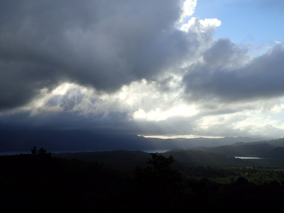 Nuages brumeux au-dessus d'une vallée luxuriante vue depuis un point de vue élevé.
