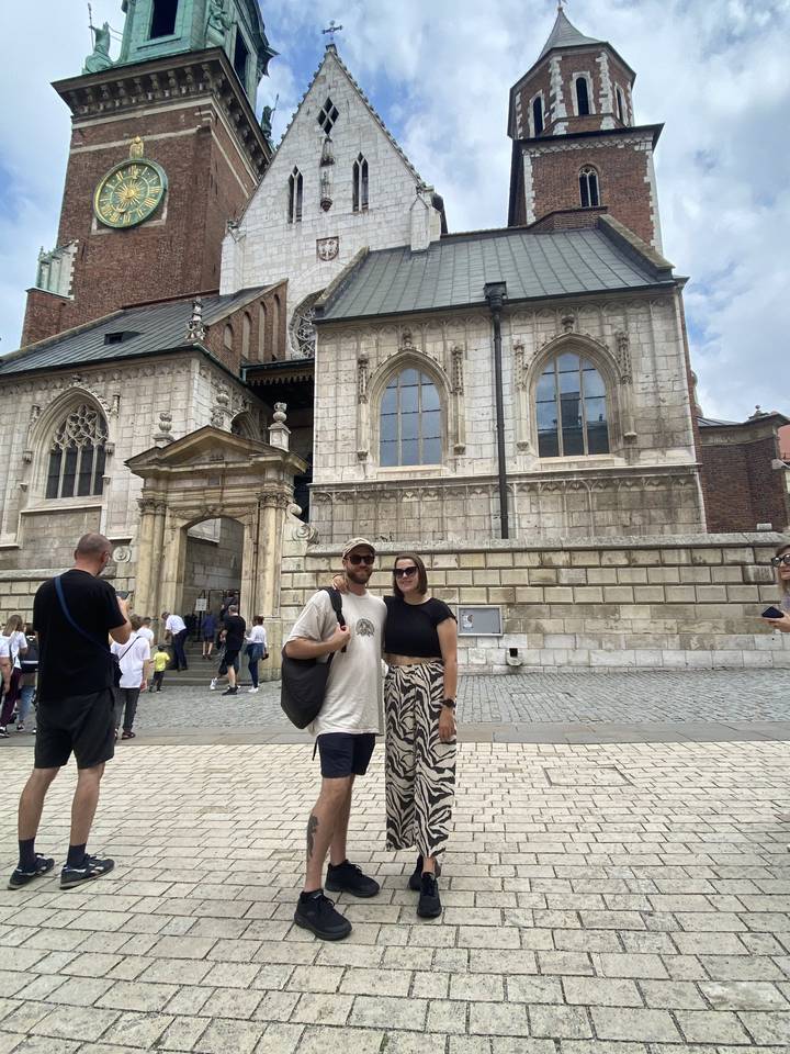 Deux personnes posant devant un ancien bâtiment architectural.