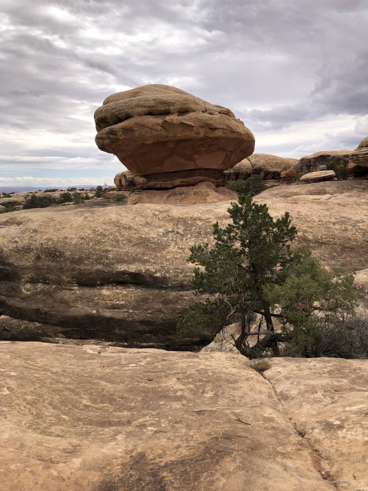 Gros rocher en équilibre dans un paysage désertique.