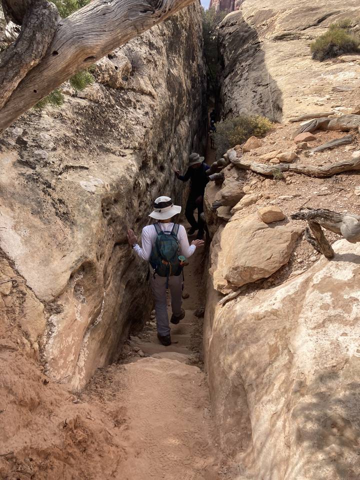 Des gens qui escaladent à travers un passage étroit de canyon.