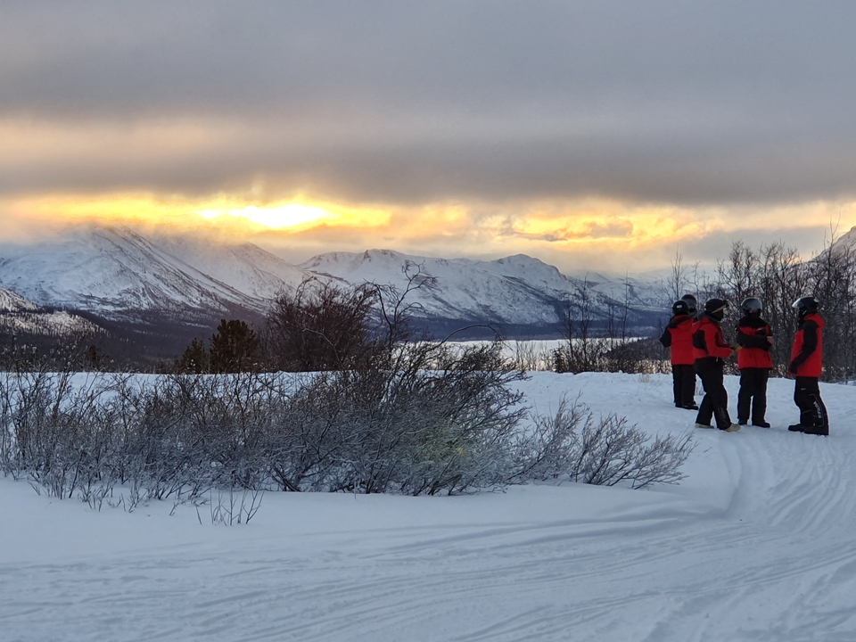 Groupe de personnes regardant un coucher de soleil sur des montagnes enneigées