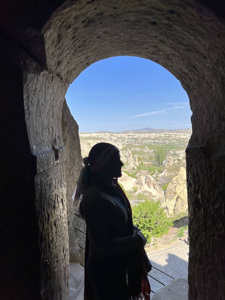 Personne debout à l'entrée d'une grotte avec vue sur le paysage extérieur.