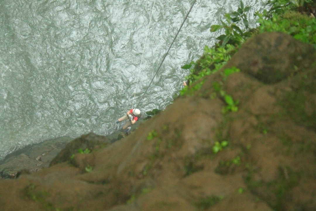 Personne qui fait de la descente en rappel le long d'une cascade.