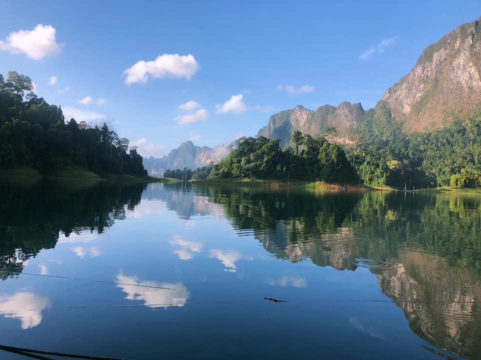 Lac serein avec des montagnes qui se reflètent et un ciel dégagé.