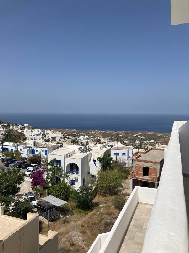 Vue de colline sur des bâtiments blancs et la mer bleue.
