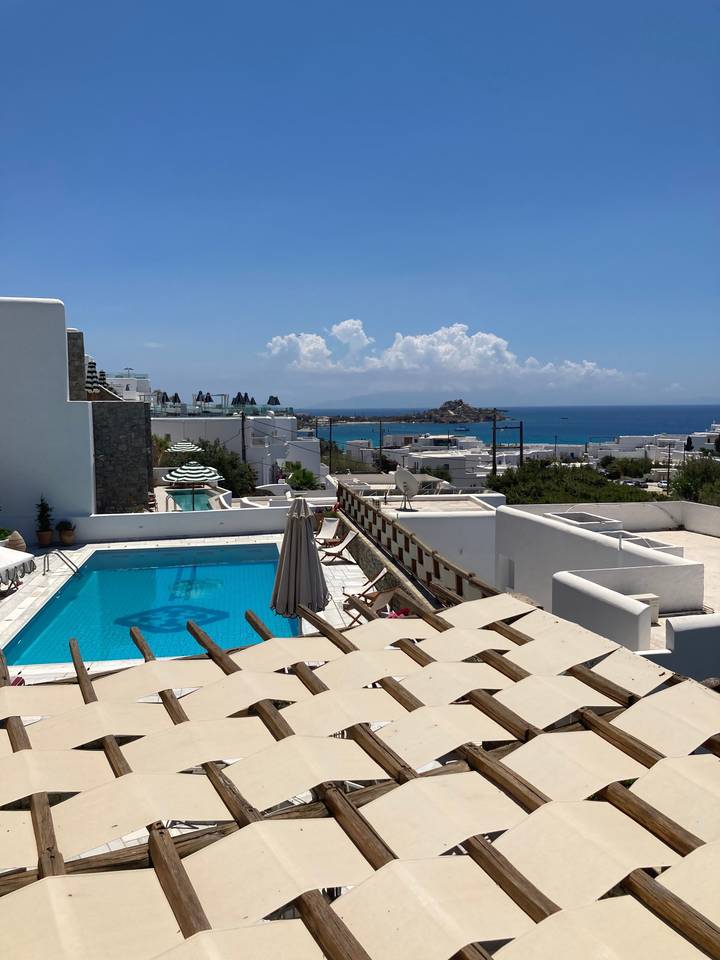 Vue sur les toits et une piscine avec la mer en arrière-plan.