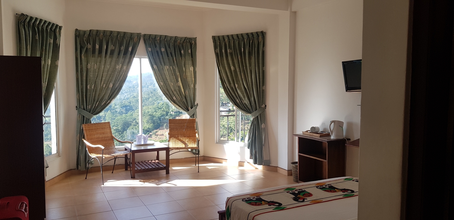 Intérieur d'une chambre d'hôtel avec de grandes fenêtres offrant une vue.