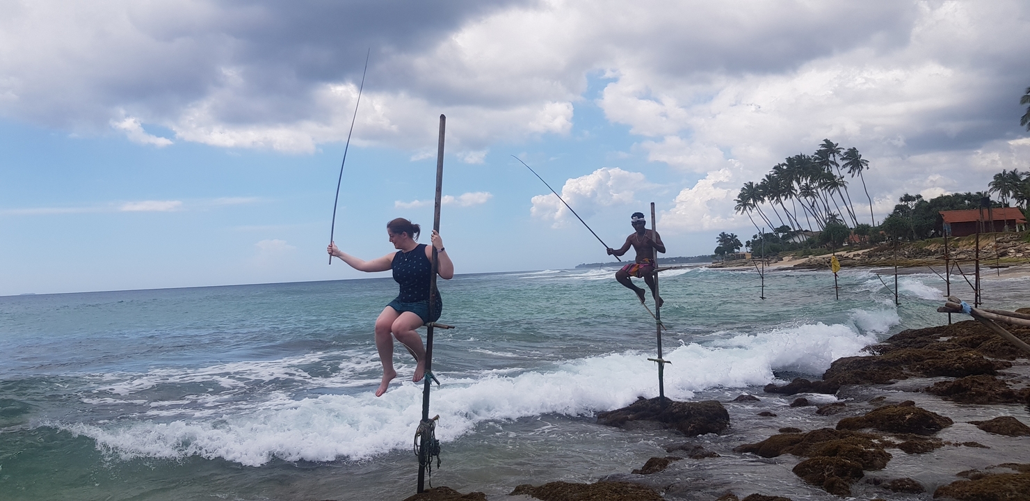 Des gens pratiquant la pêche traditionnelle sur échasses au bord de l'océan.