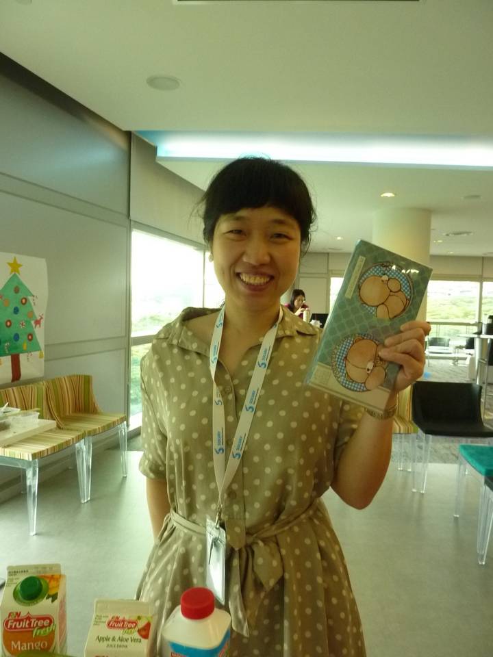 Smiling person holding a handmade craft.