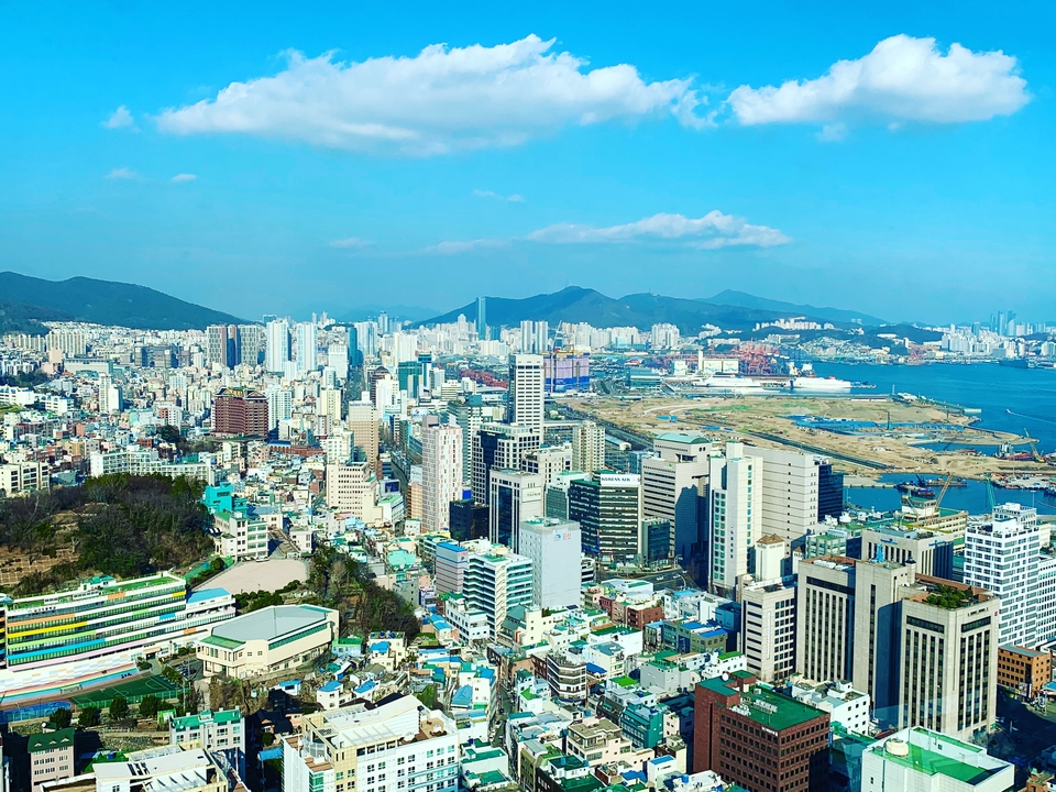 Vue aérienne d'une ville côtière avec des bâtiments modernes et des navires amarrés.