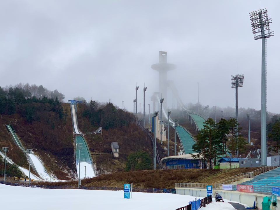 Installation sportive d'hiver avec tremplins de saut à ski enveloppés de brume.