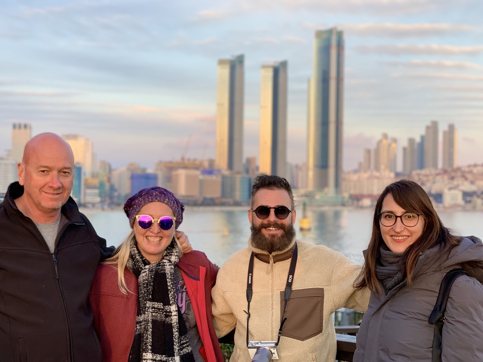 Un groupe de personnes souriantes avec un horizon pittoresque et de hauts bâtiments en arrière-plan.