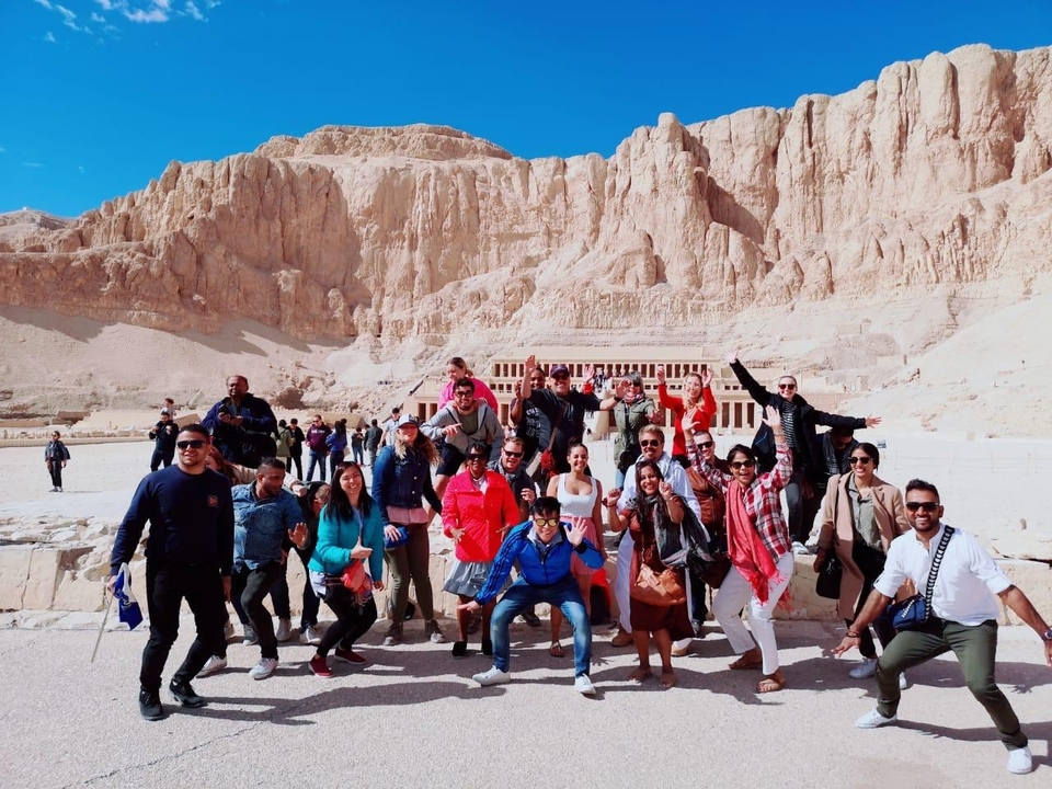 Groupe de personnes enthousiastes posant devant un temple égyptien.
