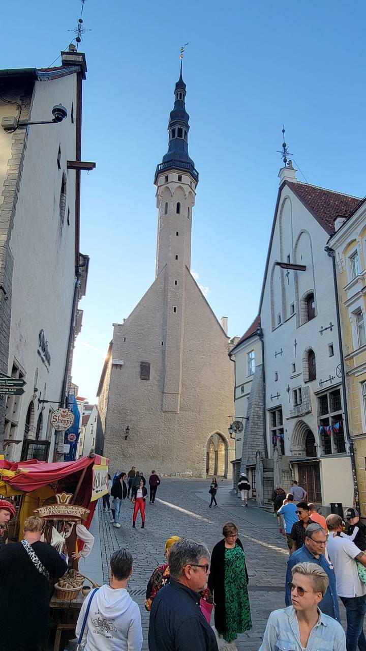 A busy street with a tall spire and people engaging in activities.
