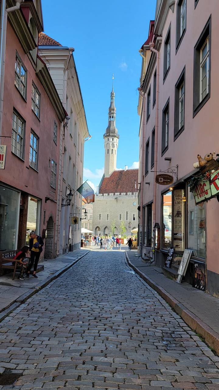 Street view with tall spire and pastel-colored buildings.