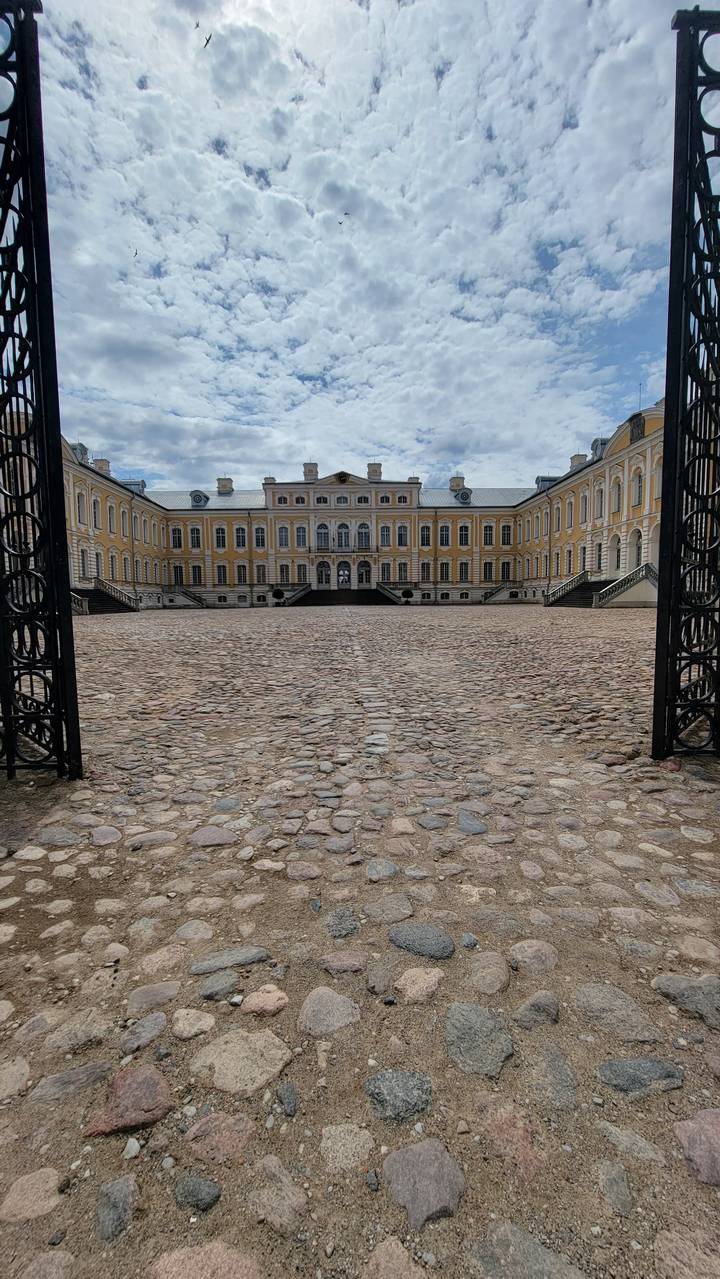 A historic building viewed through a cobblestone corridor.