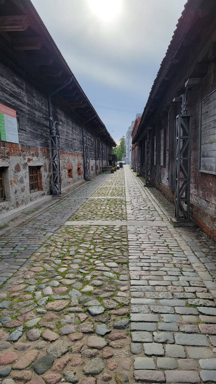Narrow cobbled path between wooden buildings.