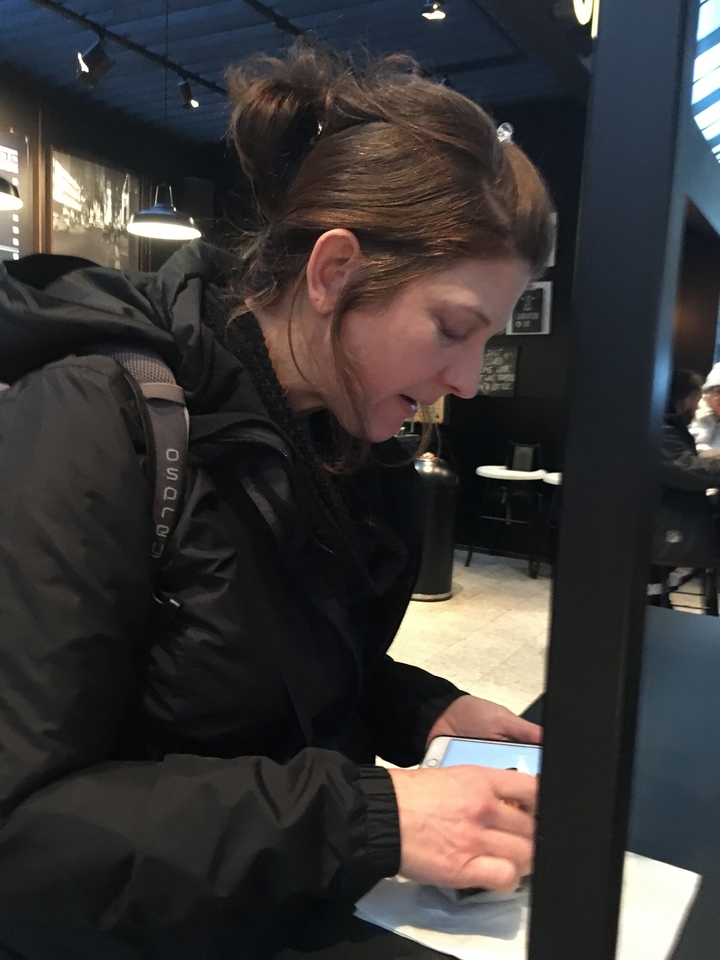 Personne dans un café portant un sac à dos et une veste