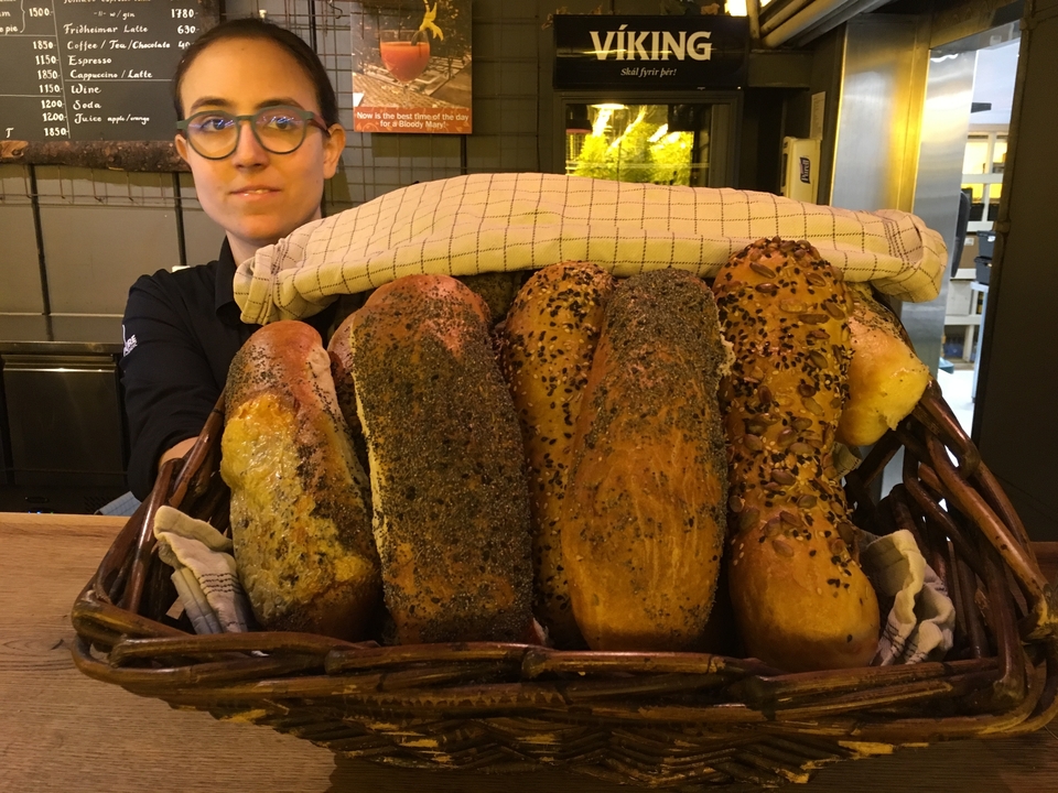 Panier de pains variés aux graines avec une personne en arrière-plan